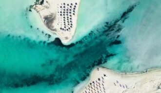 Stunning aerial photograph of Elafonissi Beach, showcasing turquoise waters, sandy shores, and sun umbrellas.