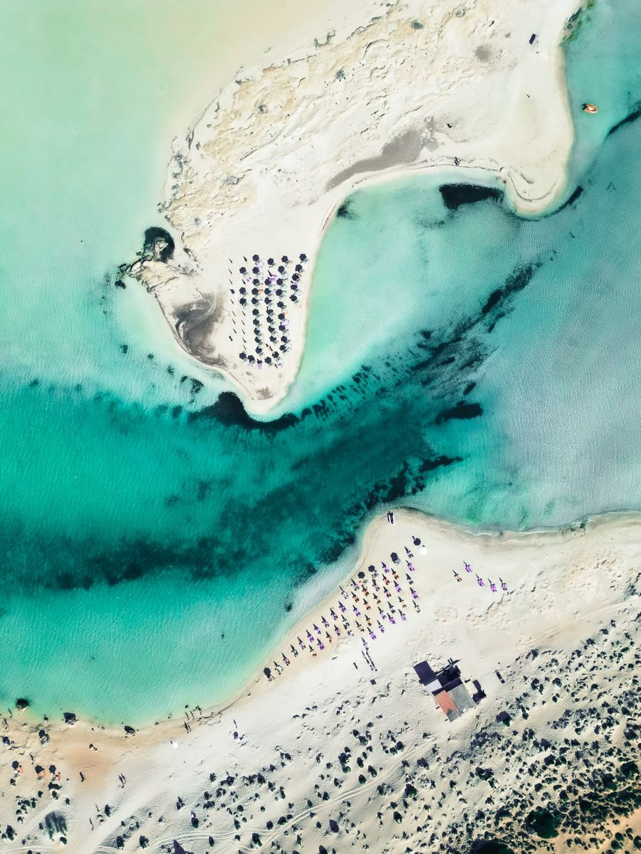 Stunning aerial photograph of Elafonissi Beach, showcasing turquoise waters, sandy shores, and sun umbrellas.