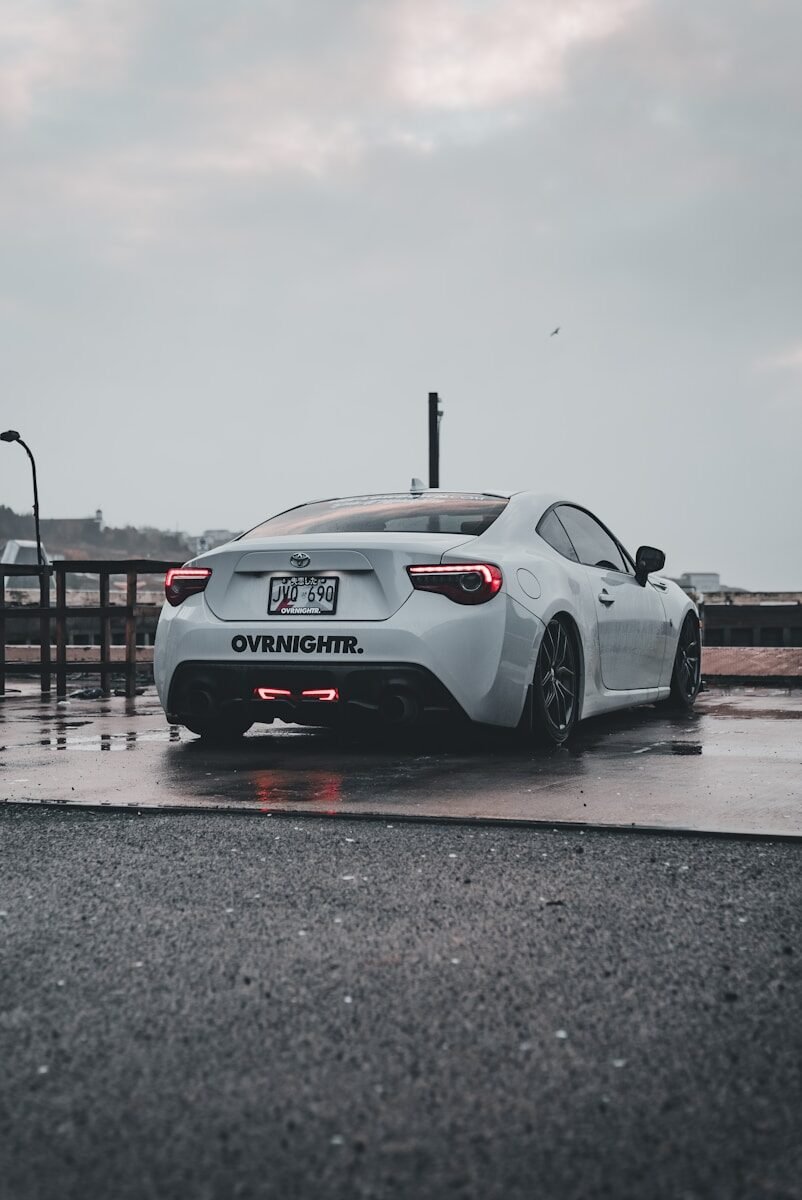 A white sports car parked on a wet parking lot