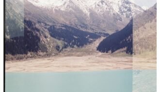 Turquoise lake, snowy mountains, and people on a rocky outcrop.