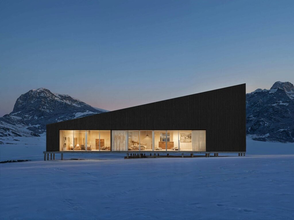 Modern building with warm lights in a snowy mountain landscape.