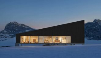 Modern building with warm lights in a snowy mountain landscape.