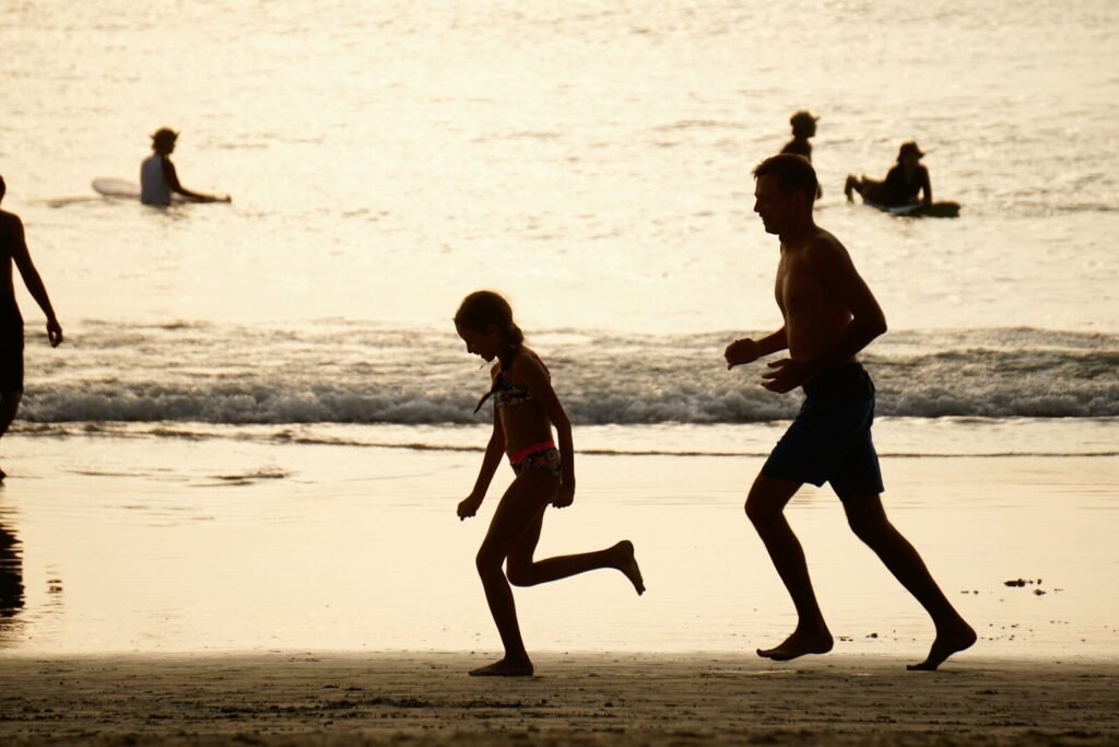 People run on the beach at sunset.