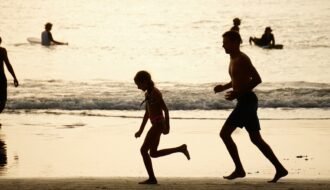 People run on the beach at sunset.