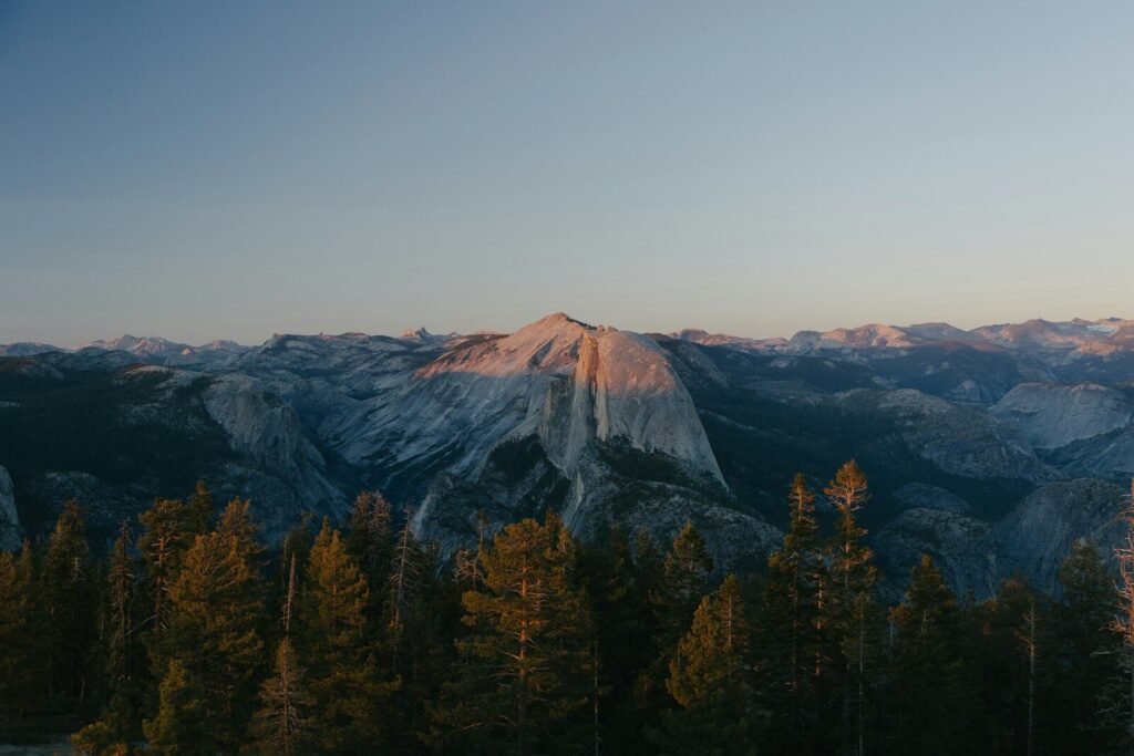 Half dome mountain at sunset with pine trees.