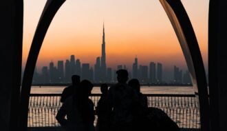 Silhouettes watch sunset over dubai skyline and burj khalifa.
