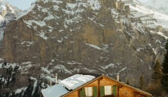 A cozy wooden house nestled in snowy mountains.
