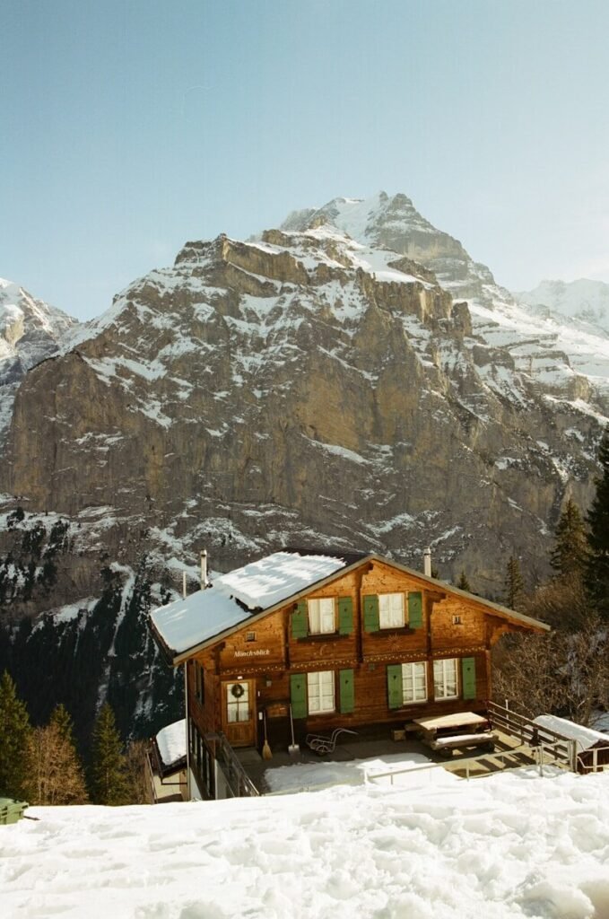 A cozy wooden house nestled in snowy mountains.