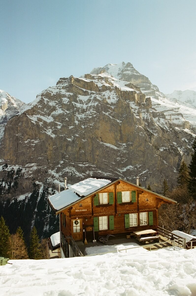 A cozy wooden house nestled in snowy mountains.
