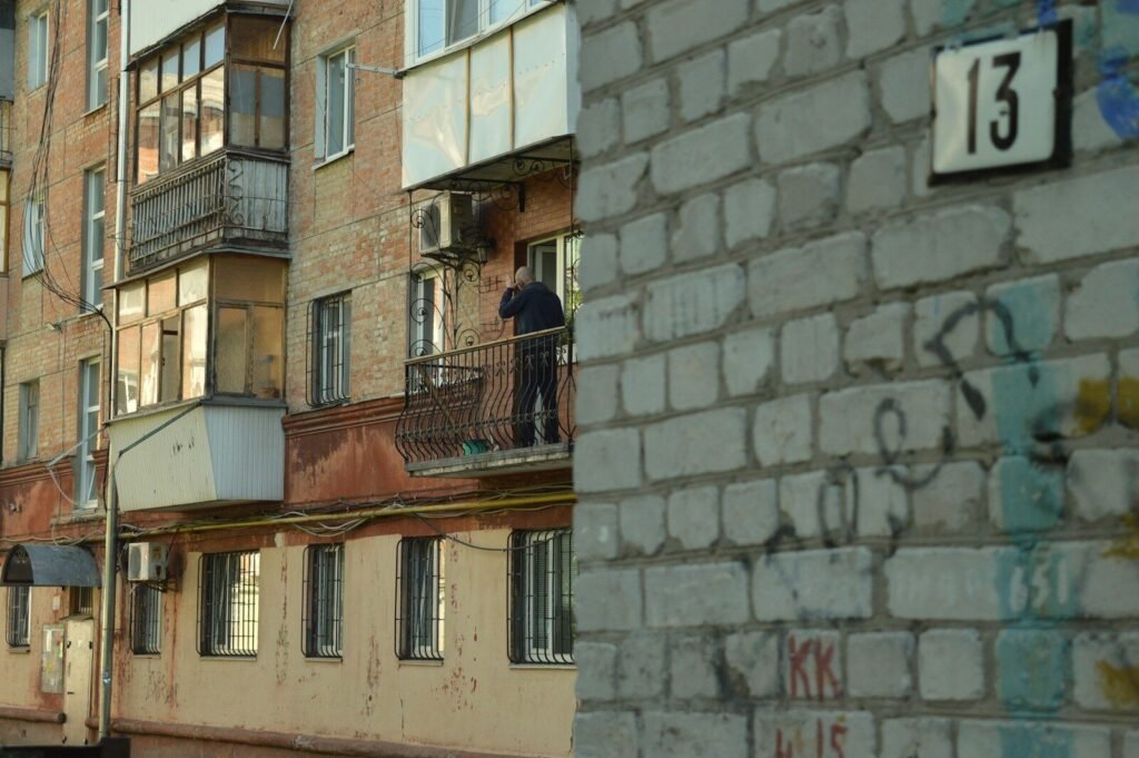 a man standing on a balcony next to a building