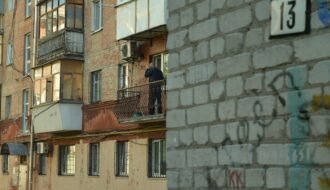 a man standing on a balcony next to a building