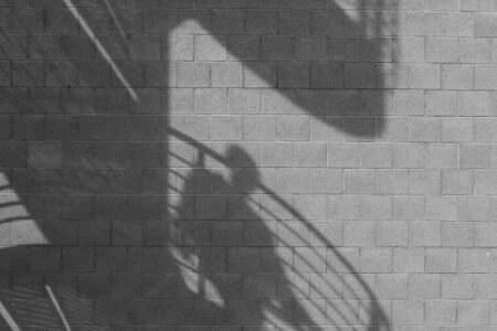 Spiral staircase and person shadows cast on a brick wall.