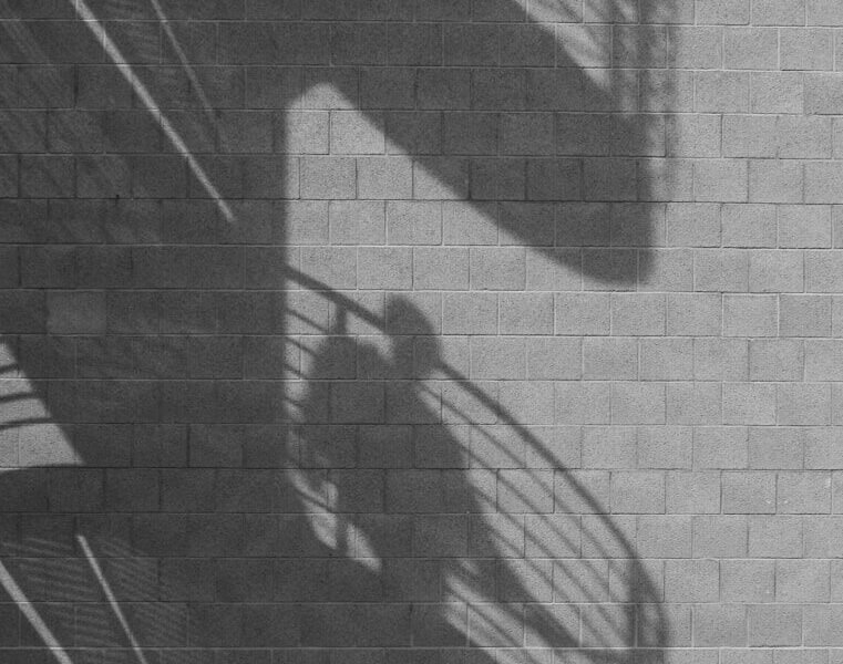 Spiral staircase and person shadows cast on a brick wall.