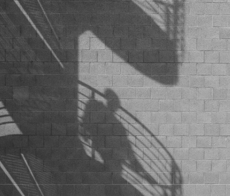 Spiral staircase and person shadows cast on a brick wall.