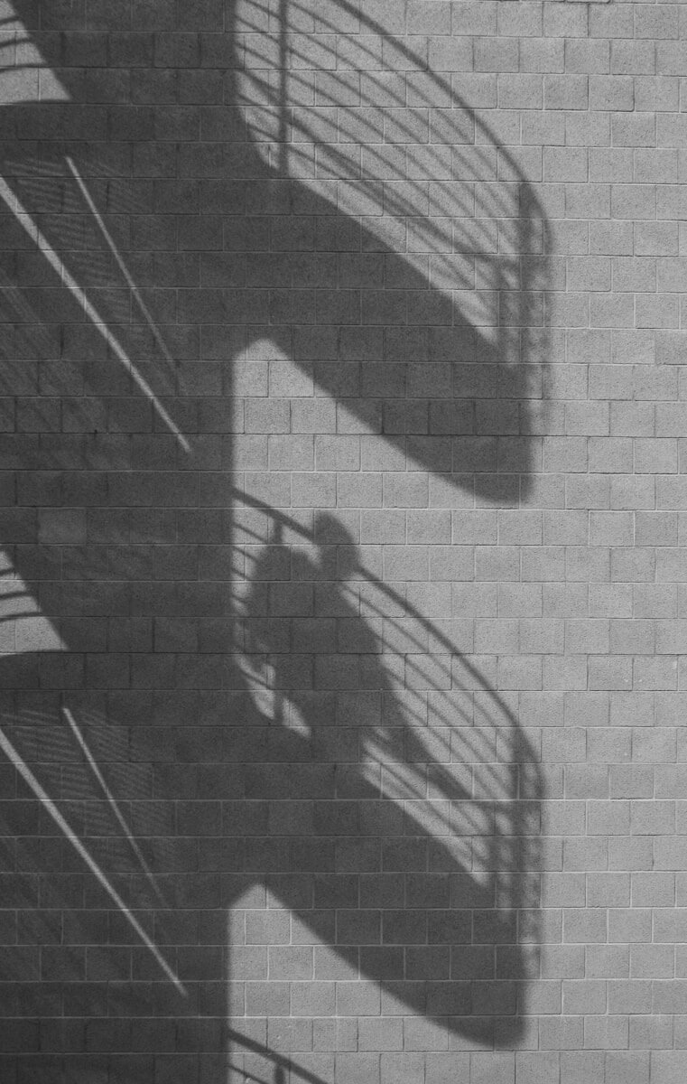 Spiral staircase and person shadows cast on a brick wall.