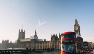 red double-decker bus passing Palace of Westminster, London during daytime