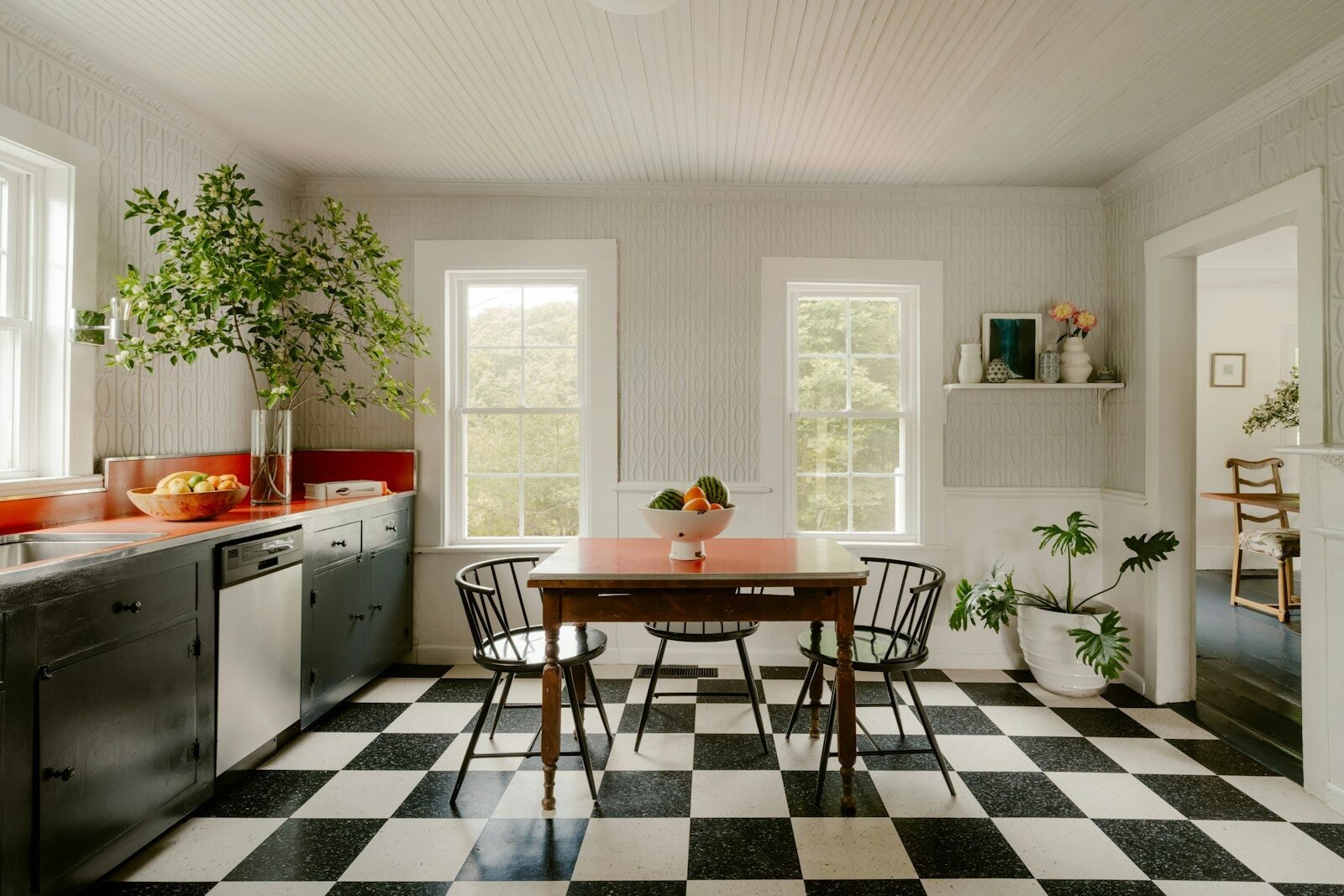 Bright kitchen with checkered floor, dining table, and large windows.