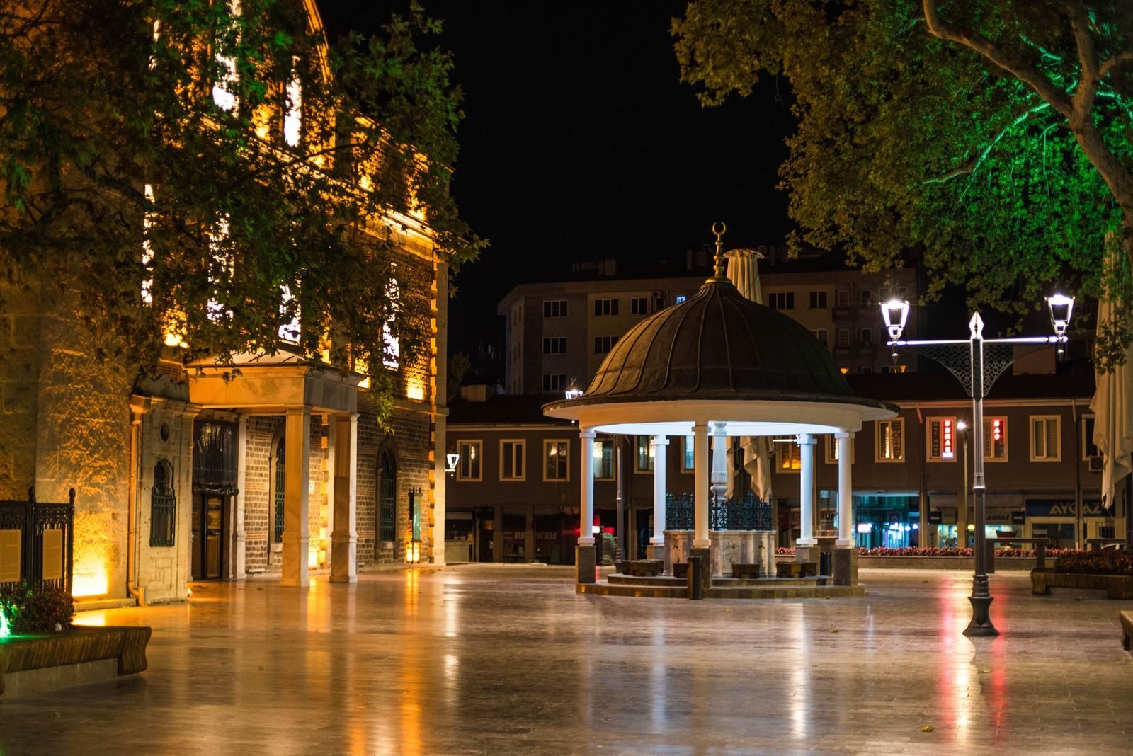 Illuminated night view of a plaza in Balıkesir, Türkiye, showcasing elegant architecture and peaceful ambiance.