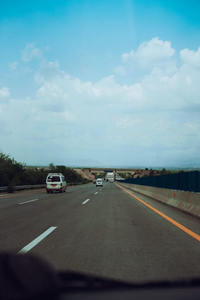 Vehicles cruise on a spacious highway under a bright blue sky, showcasing modern transportation.