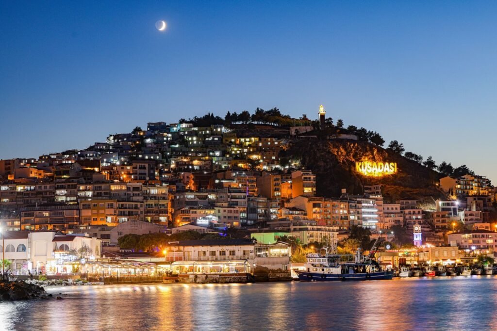 Stunning view of Kuşadası illuminated at night with a crescent moon.