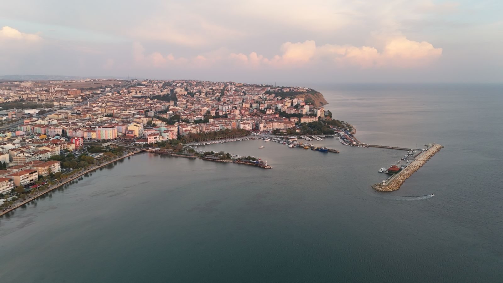 A picturesque aerial view of a coastal city and harbor at dusk.