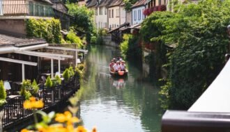 Beautiful sunny day on a canal in Colmar, France, featuring colorful houses and a boat ride.