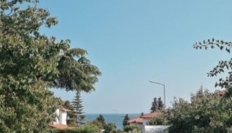 A picturesque street in Tekirdağ with ocean view and greenery, capturing a summer's day.