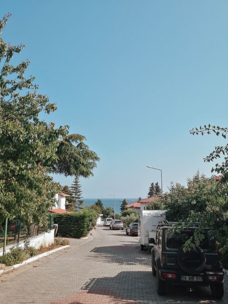 A picturesque street in Tekirdağ with ocean view and greenery, capturing a summer's day.