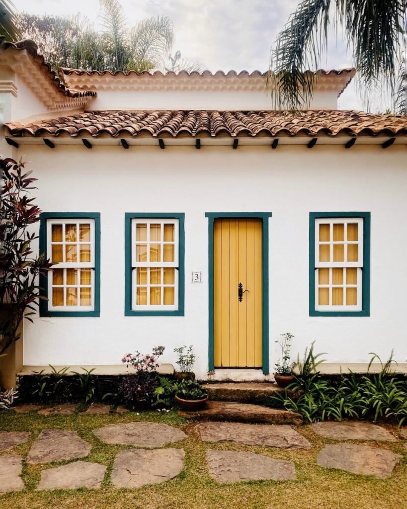 Beautiful colonial house with a vibrant yellow door and lush garden area.