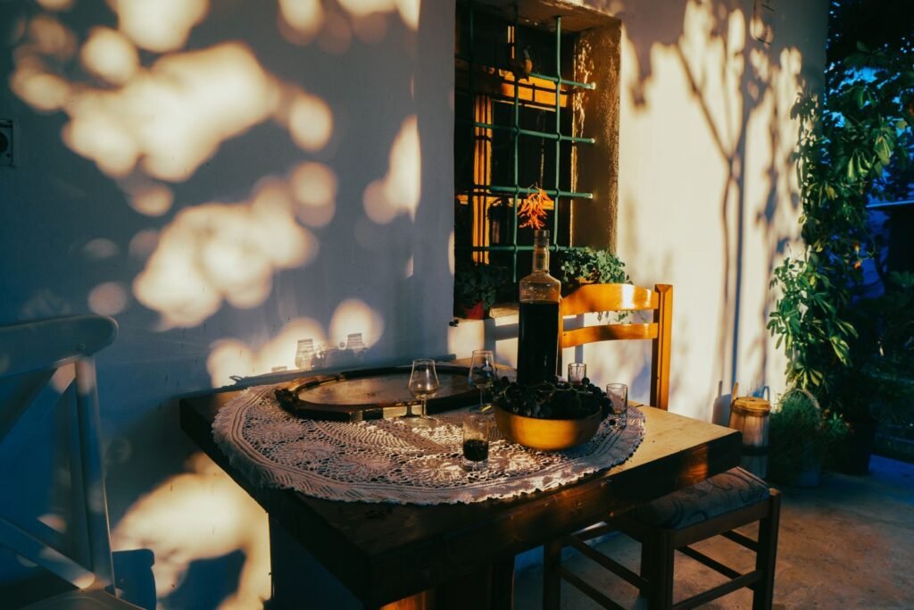 Charming patio setup in Fishtë, Albania during golden hour, featuring a table with a bottle and glasses.