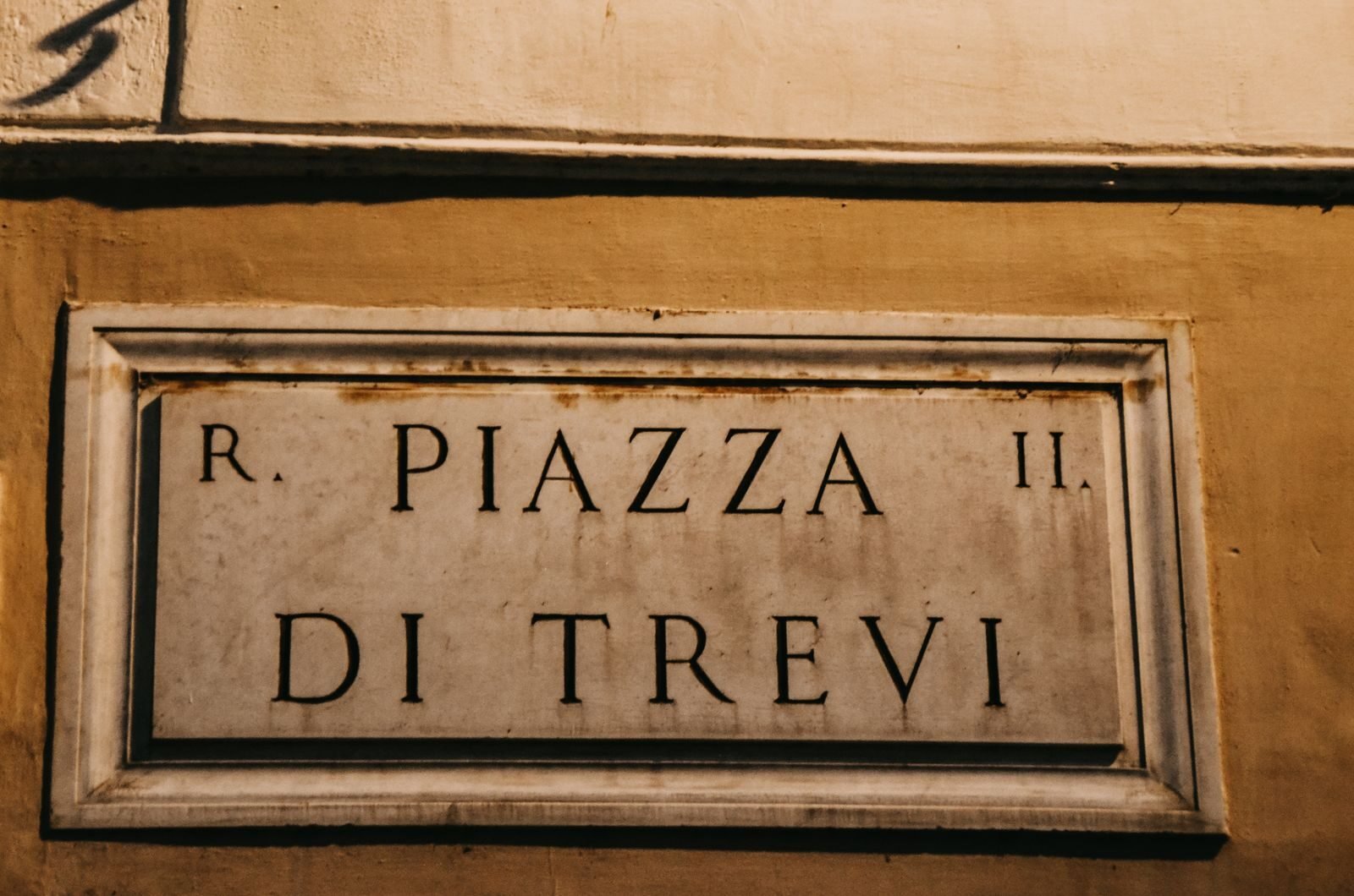 Close-up of Piazza di Trevi sign in Rome, showcasing historical architecture.