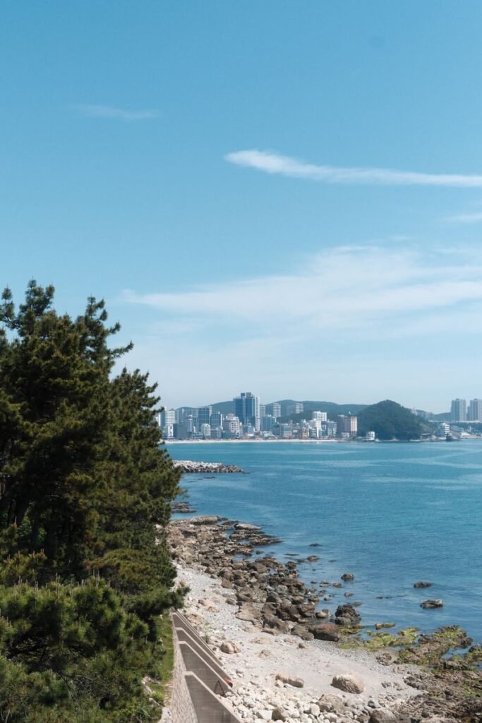 A picturesque view of a coastal skyline in South Korea with clear blue waters and lush greenery.