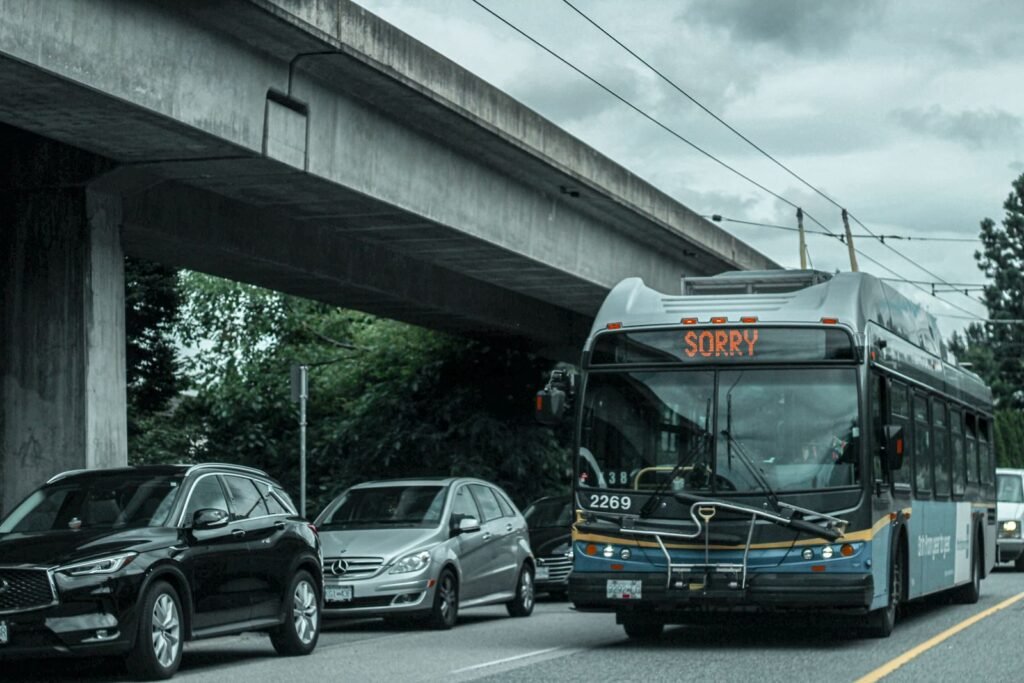 A busy city street with traffic and a bus showing 'SORRY' on its display under an overpass.