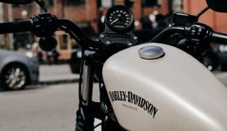 Retro styled white motorcycle with black handlebar parked on sunny street in city