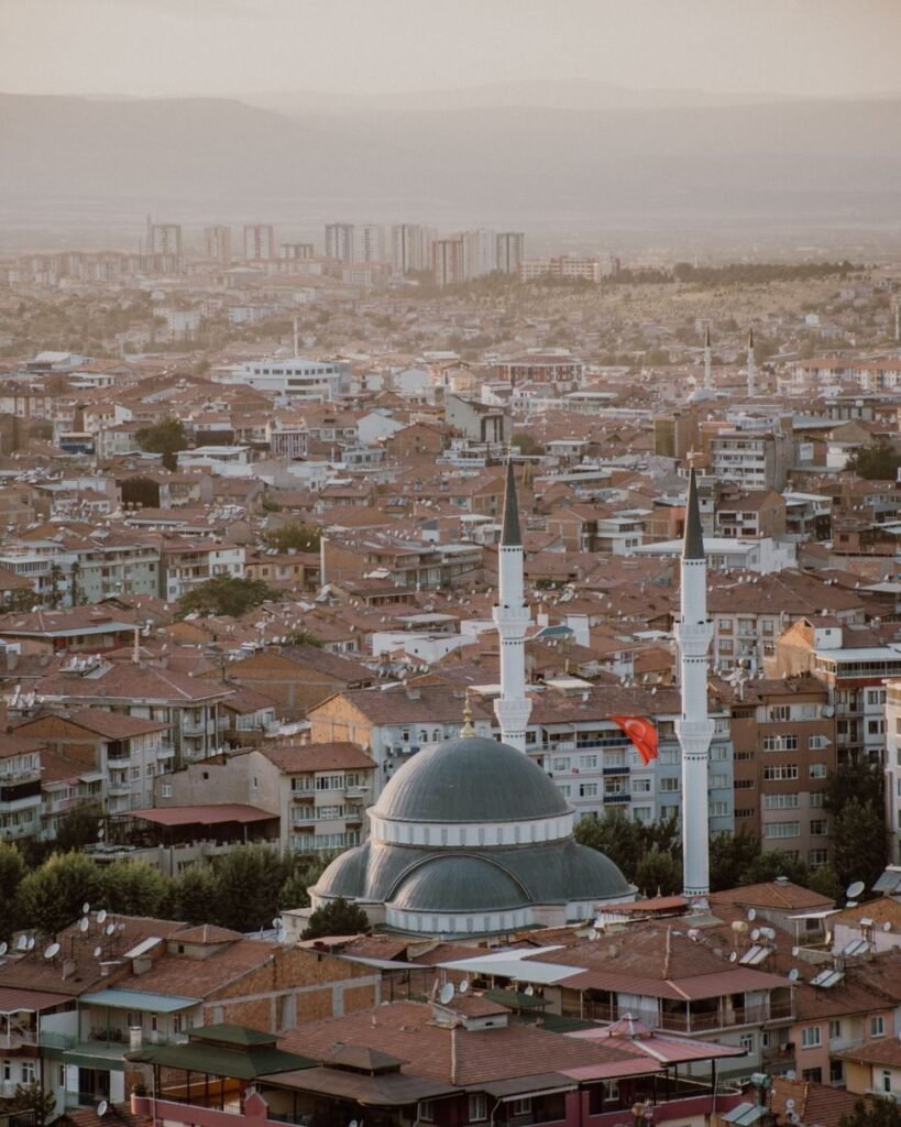 High-angle shot of a cityscape with a prominent mosque and two minarets at sunset.