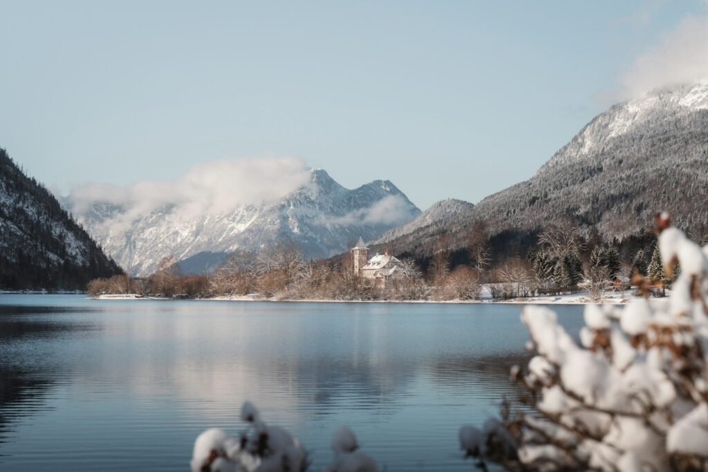 Snow-covered mountains rise above a tranquil lake in winter.