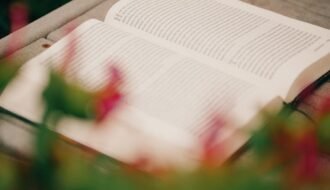 Open book on wood with blurred flowers