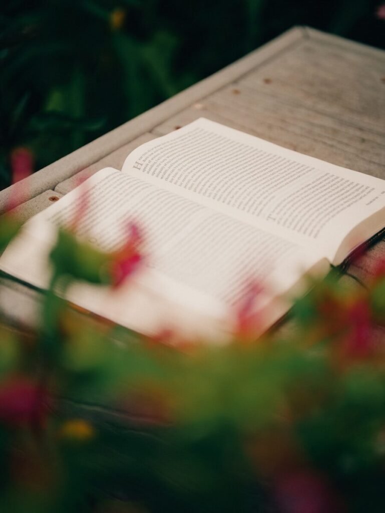 Open book on wood with blurred flowers