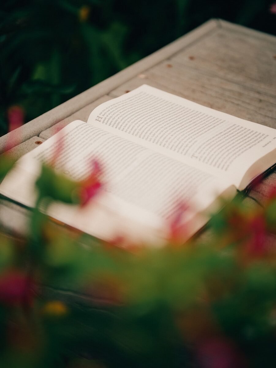 Open book on wood with blurred flowers