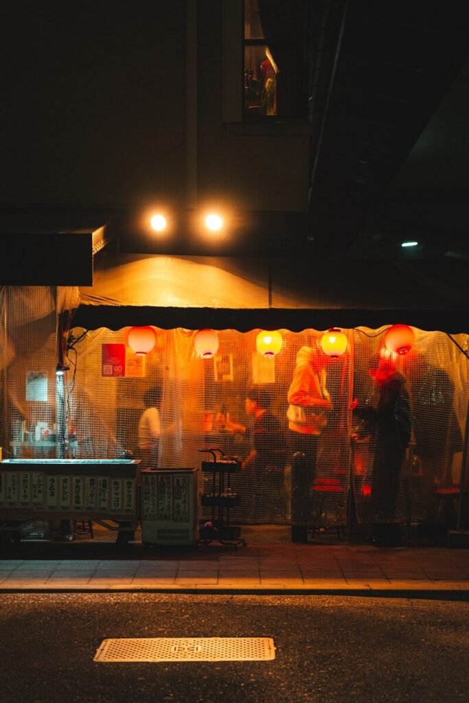 Warmly lit street food stall with red lanterns at night.