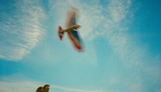 A small plane performs aerobatics in a blue sky.