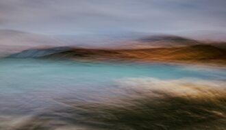 Abstract blurred landscape with blue water and brown hills.