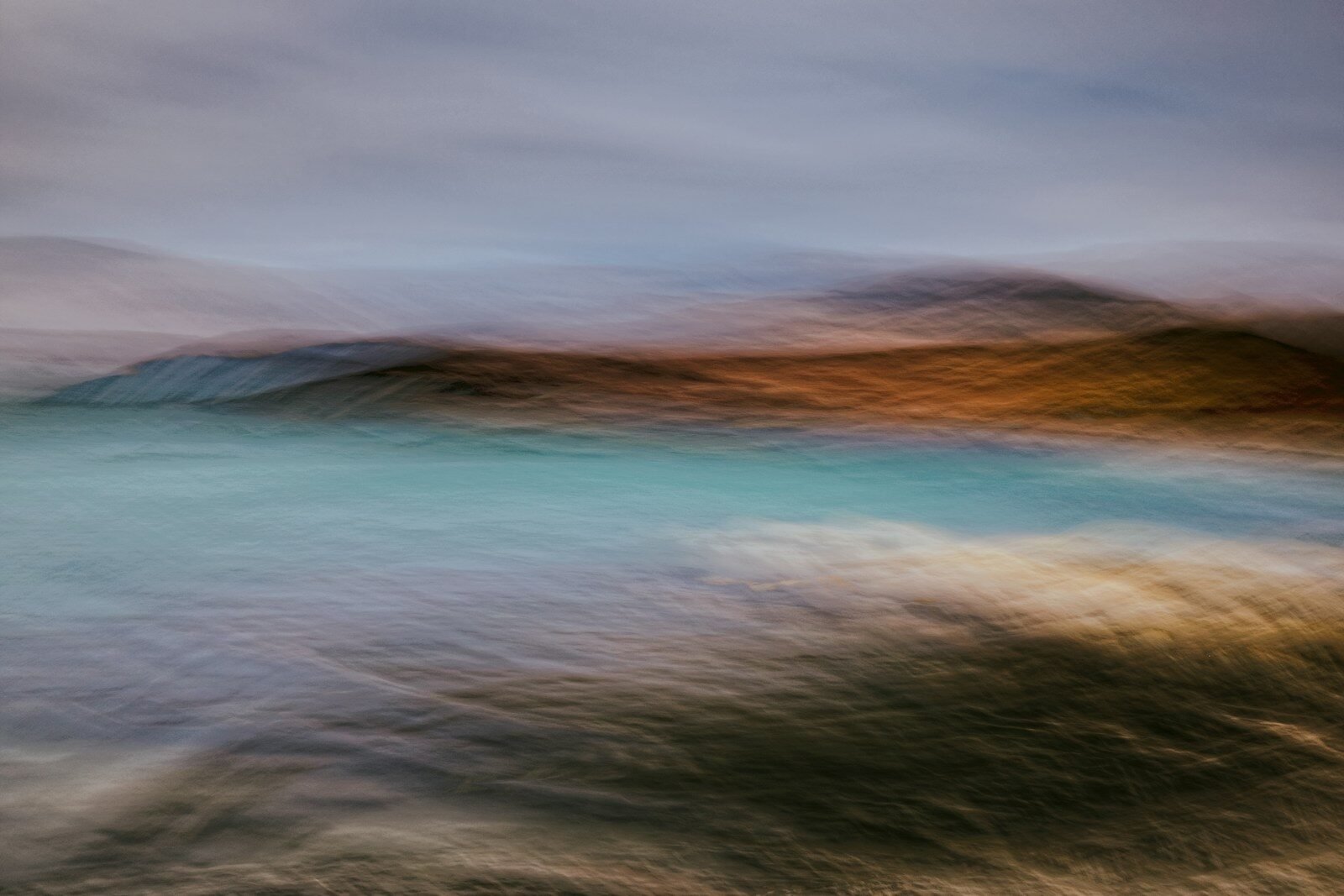 Abstract blurred landscape with blue water and brown hills.