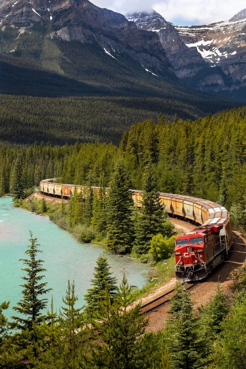 red and white train on rail near body of water during daytime